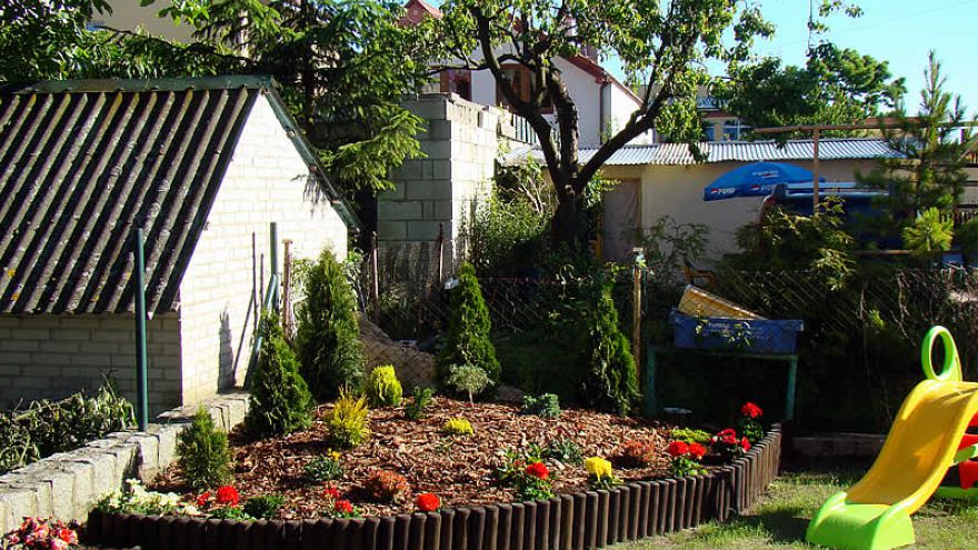 Ogród wypoczynkowy w Villi California w Darłówku z dużą ilością kwiatów i roślin.